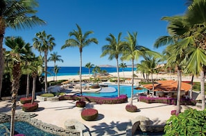 En resort med central swimmingpool, palmer og havudsigt.