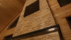 A stone fireplace with a fire burning inside, set in a wooden wall with a sloped ceiling. - Mandala Bliss Mongolia (Ulaanbaatar)