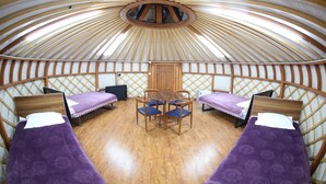 A yurt with four beds, a central wooden table, and a circular skylight. - Mandala Bliss Mongolia (Ulaanbaatar)