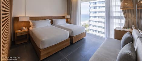 Ein Hotelzimmer mit zwei Betten, einem Deckenventilator, einem großen Fenster mit Vorhängen und Blick auf die Stadt.