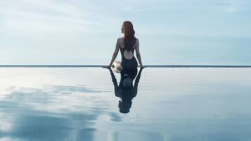 A person sitting on a reflective surface with a clear sky in the background.