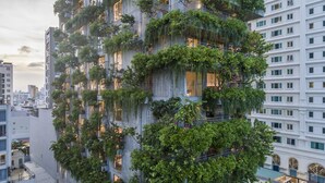 Um edifício alto com jardins verticais extensos e varandas.