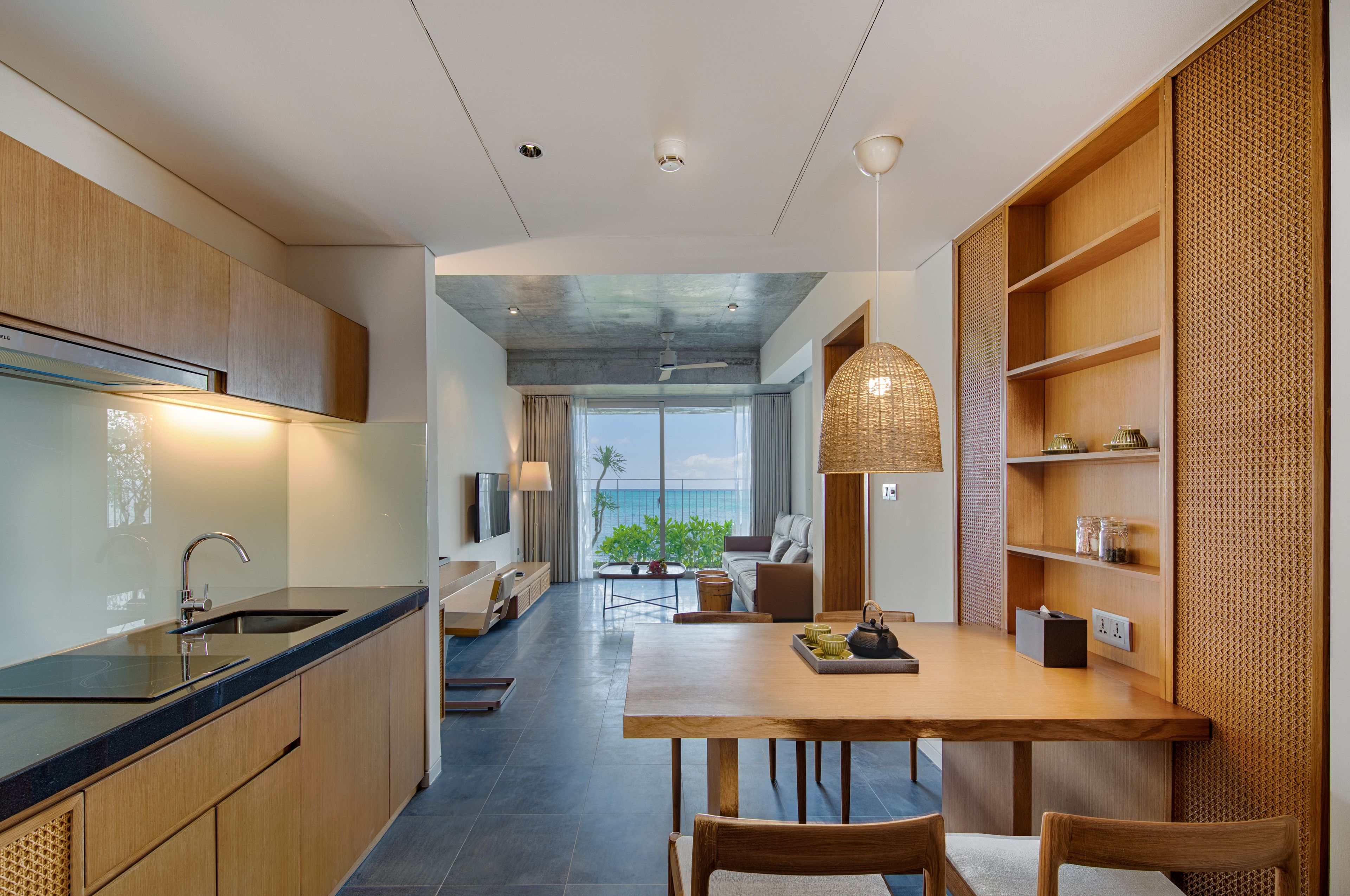 A modern kitchen with a dining area, large windows, and a view of the outdoors.