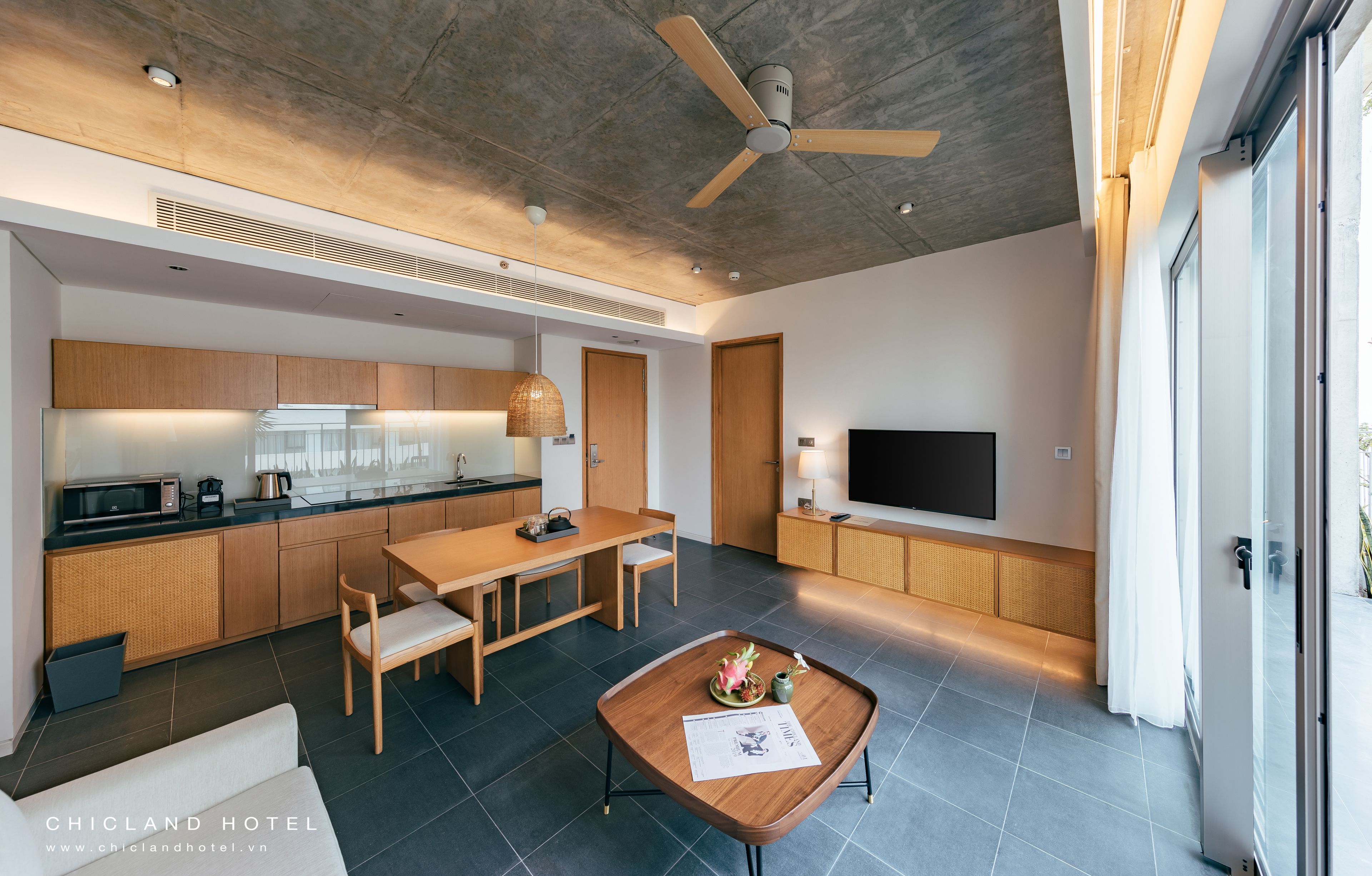 A modern kitchen with a dining area, a flat-screen TV, and a ceiling fan.