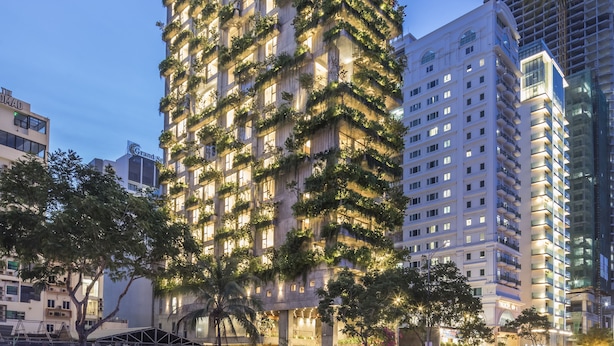 Um hotel alto com vários andares, varandas e fachada bem iluminada.