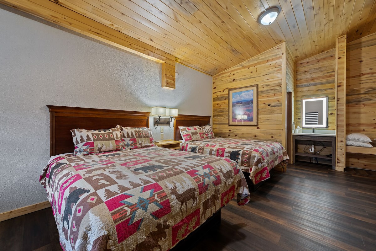 A cozy room with two beds, a painting on the wall, and a wooden ceiling.