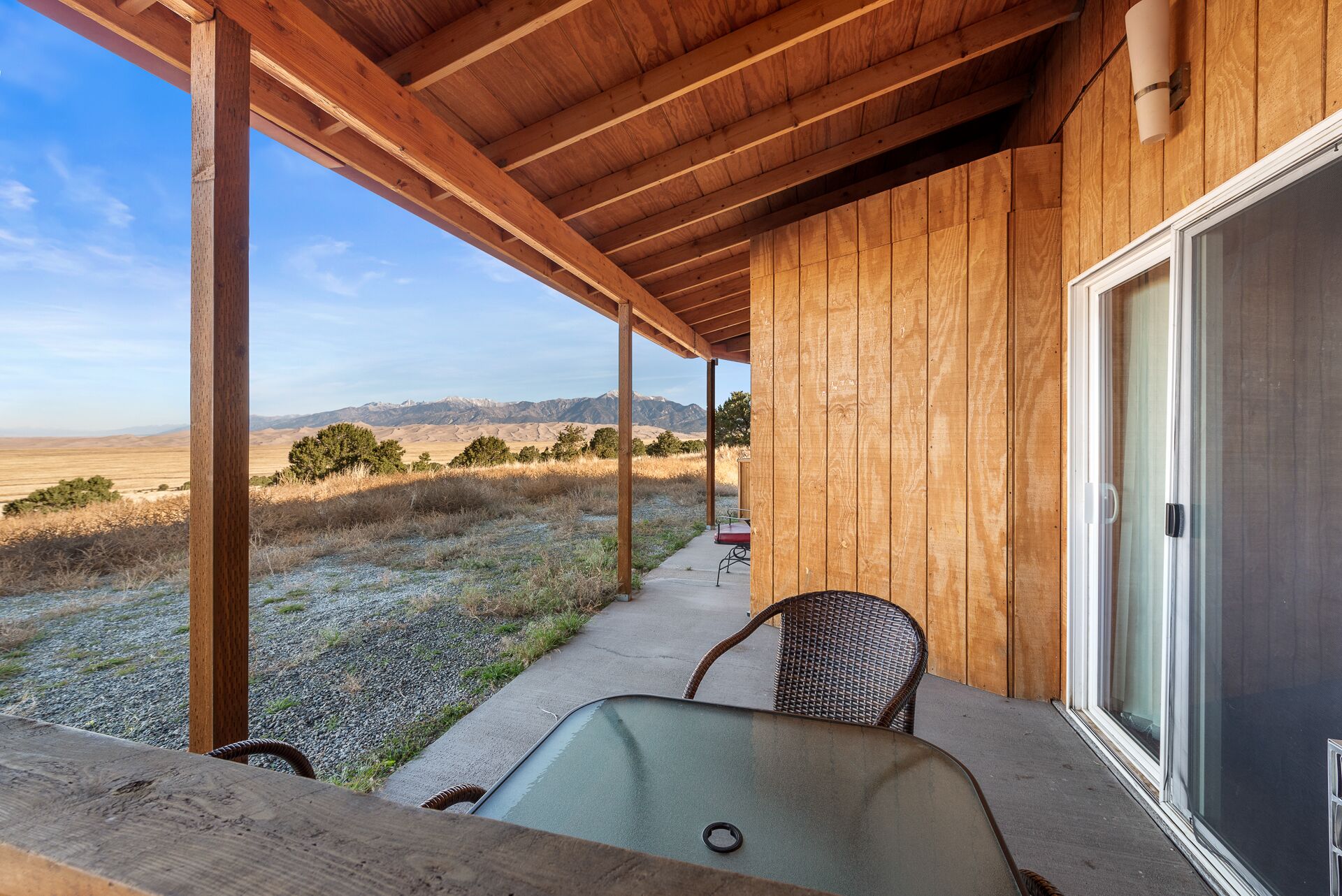 A wooden covered porch with a view of a mountainous landscape.