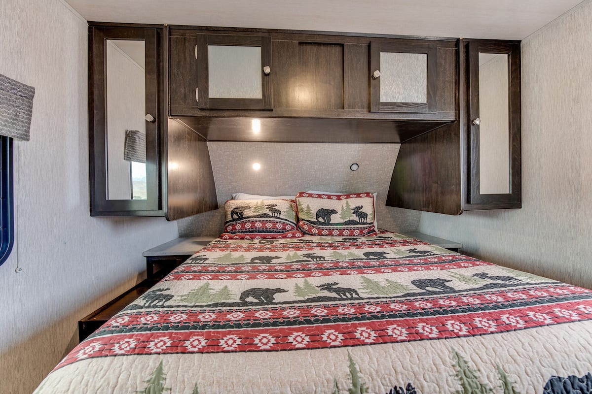 A bedroom with a bed, two pillows, a headboard, and a wardrobe.
