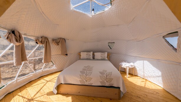 A cozy, tent-like bedroom with a large bed, a small bedside table, and a window. - Great Sand Dunes Lodge (Mosca)