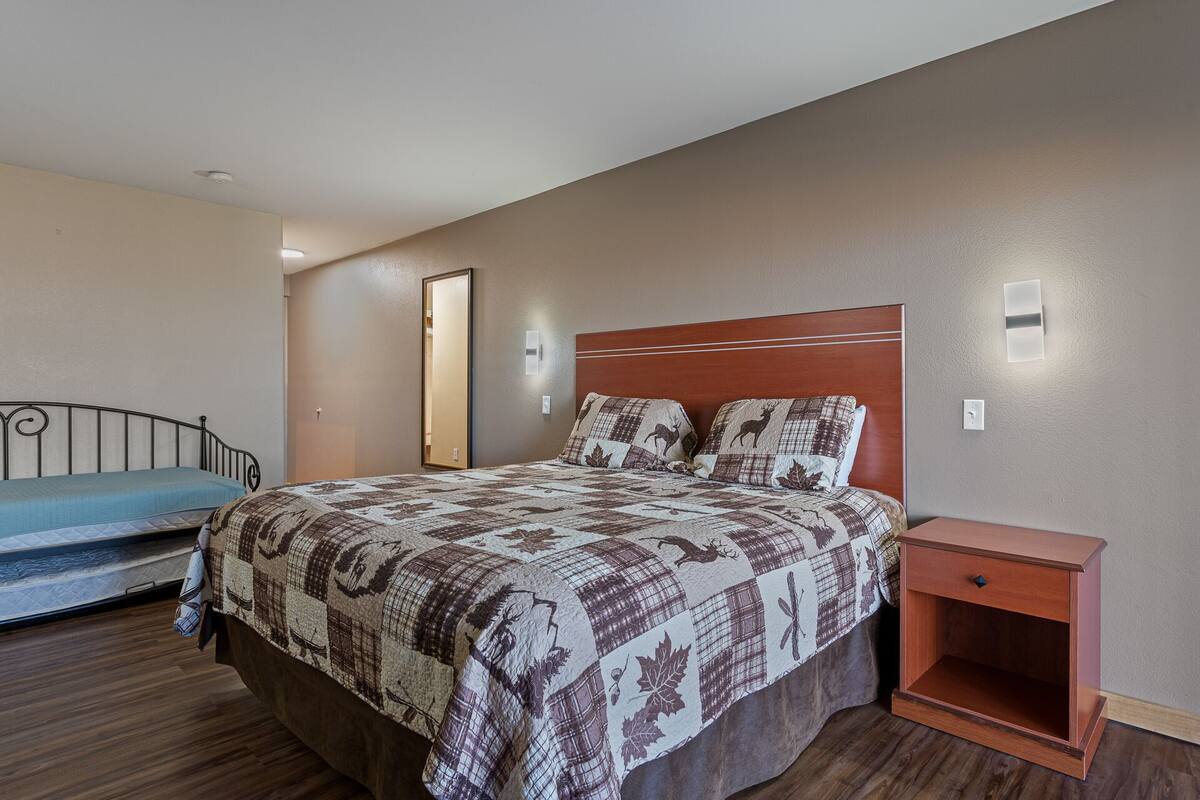 A bedroom with a bed, a nightstand, a mirror, and a wardrobe.