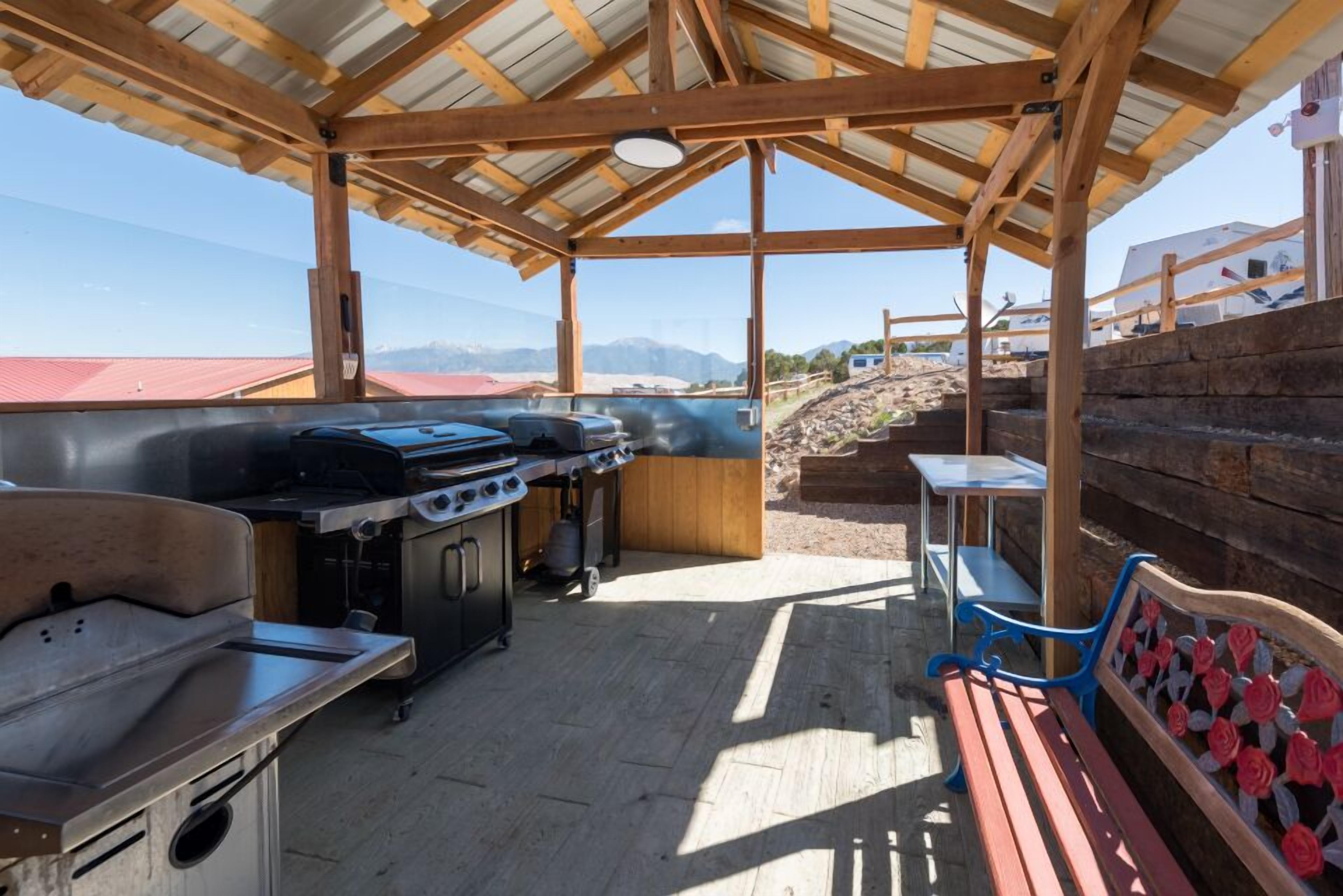 Een terras buiten, met een barbecue, een spoelbak en een bank.