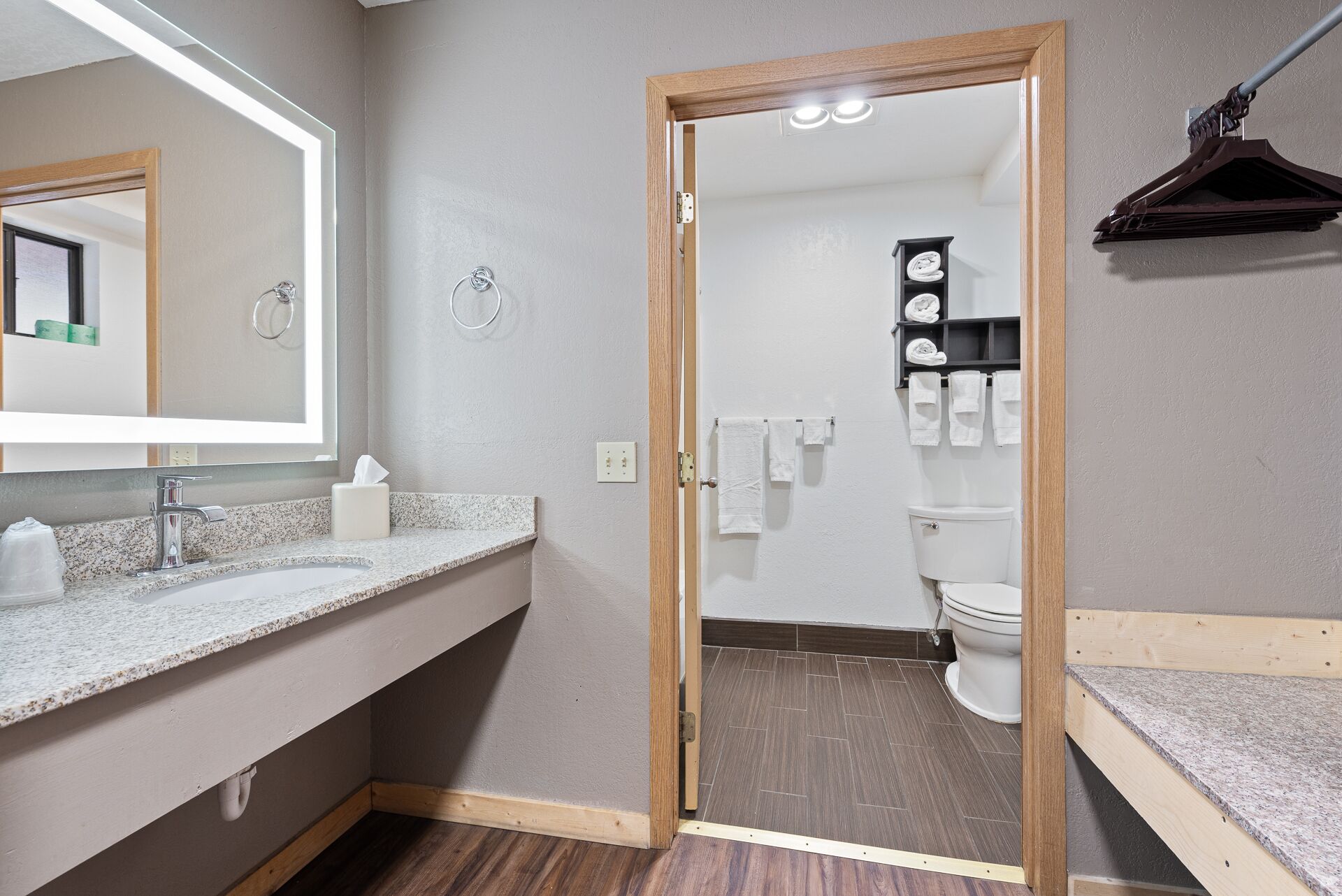 Een badkamer met een houten deur, een wastafel met spiegel en een toilet.