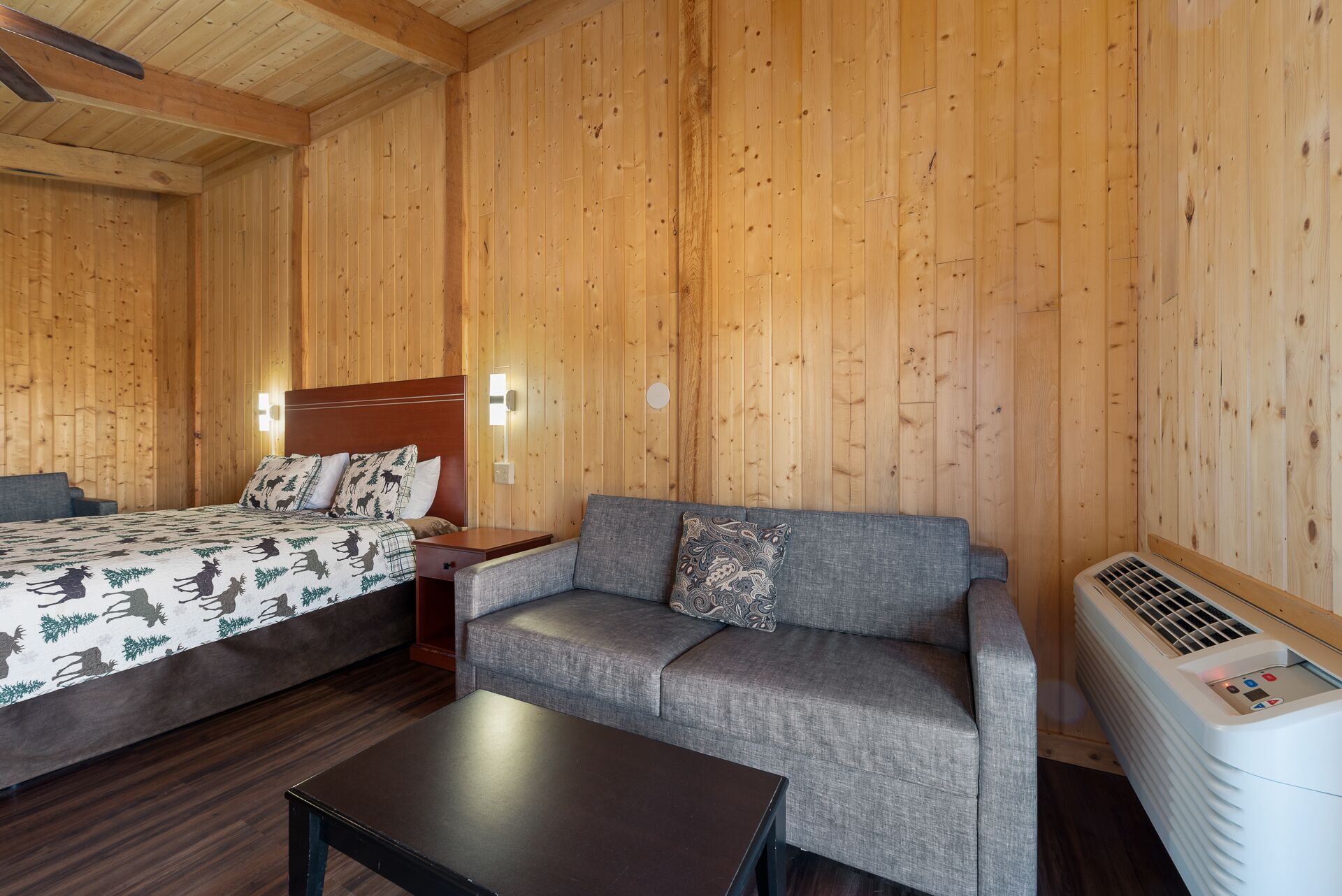 Ein Zimmer in einer Holzhütte mit einem Bett, einer Couch und einem Tisch.