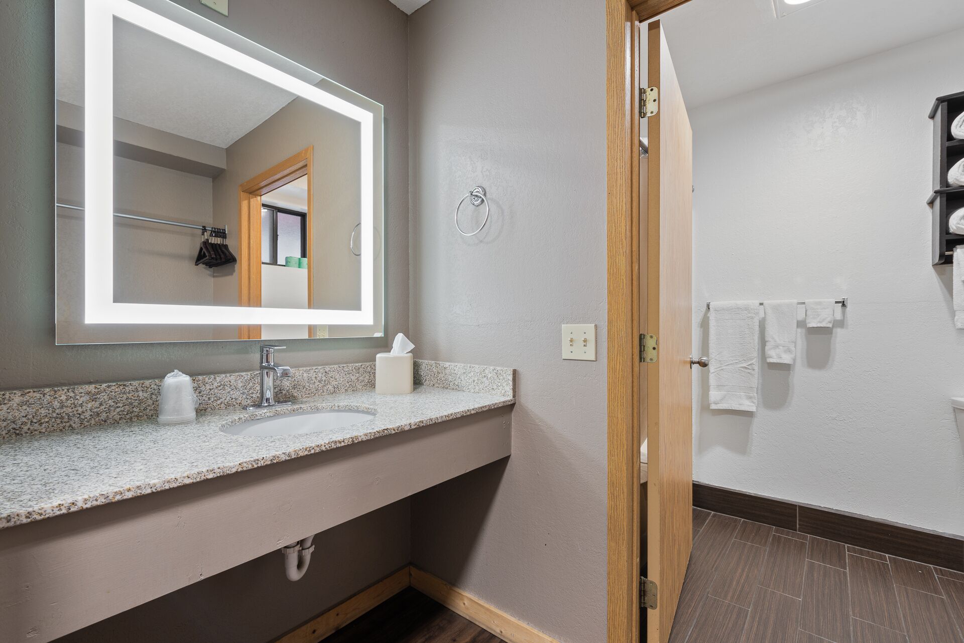 Une salle de bain avec un lavabo doté d’un plan de travail en granit, un miroir et une porte en bois.