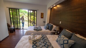 Une chambre d’hôtel avec deux lits, une grande porte-fenêtre coulissante donnant sur un balcon et une tête de lit en bois.