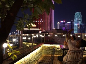 Une terrasse sur le toit, dotée d’un mur en pierre, d’une rambarde en verre et de guirlandes lumineuses.