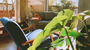 A cozy living room with a blue armchair, a guitar, and a potted plant.