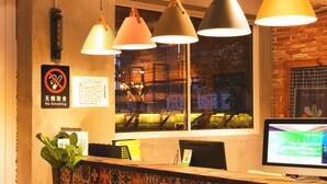 A reception desk with a computer monitor, a no-smoking sign, and a window with a view of buildings.