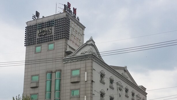 Un edificio de varios pisos con un letrero llamativo que dice "HIDAS HOTEL" en la parte superior.