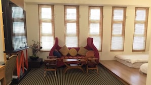 A room with a sofa, a table, and a bed. There are windows with blinds and a television on a stand. - U-Lu B&B (Hualien City)