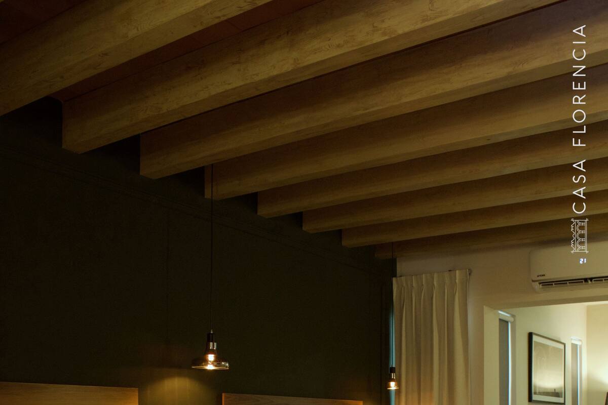 Ein Hotelzimmer mit zwei Betten, Holzkopfteilen, einer Hängelampe und einem Nachttisch mit Lampe.