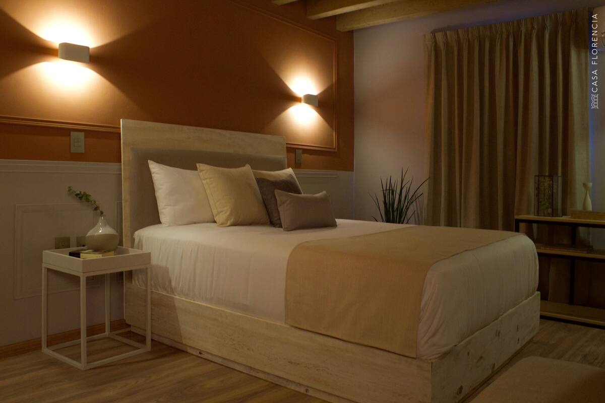 Ein Schlafzimmer mit einem großen Bett, Nachttischen und Wandleuchten.