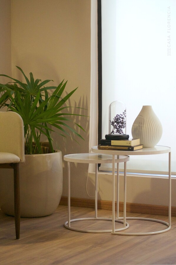 Um quarto com uma planta em vaso, uma mesa redonda com uma cúpula de vidro e um vaso.