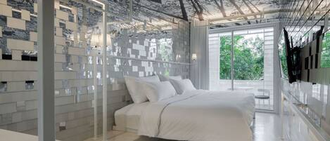 A modern bedroom with a large bed, a glass partition wall, and a view of greenery outside.