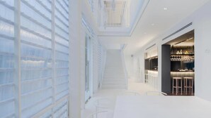 A modern interior with a central staircase, white walls, and a bar area with stools. - Little Shelter Hotel Chiangmai  (Chiang Mai)