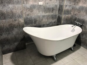 A freestanding bathtub in a bathroom with a tiled floor and walls. - Taomi 5211 B&B (Puli)