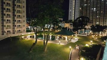 Stroll through the well-lit park surrounded by lush greenery and enjoy the serene atmosphere.