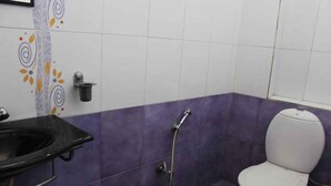 A bathroom with a white toilet, a black sink, and a shower. - FabHotel My Choice Abids (Hyderabad)