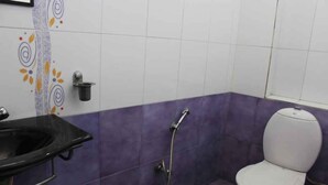 A bathroom with a white toilet, a black sink, and a shower. - FabHotel My Choice Abids (Hyderabad)