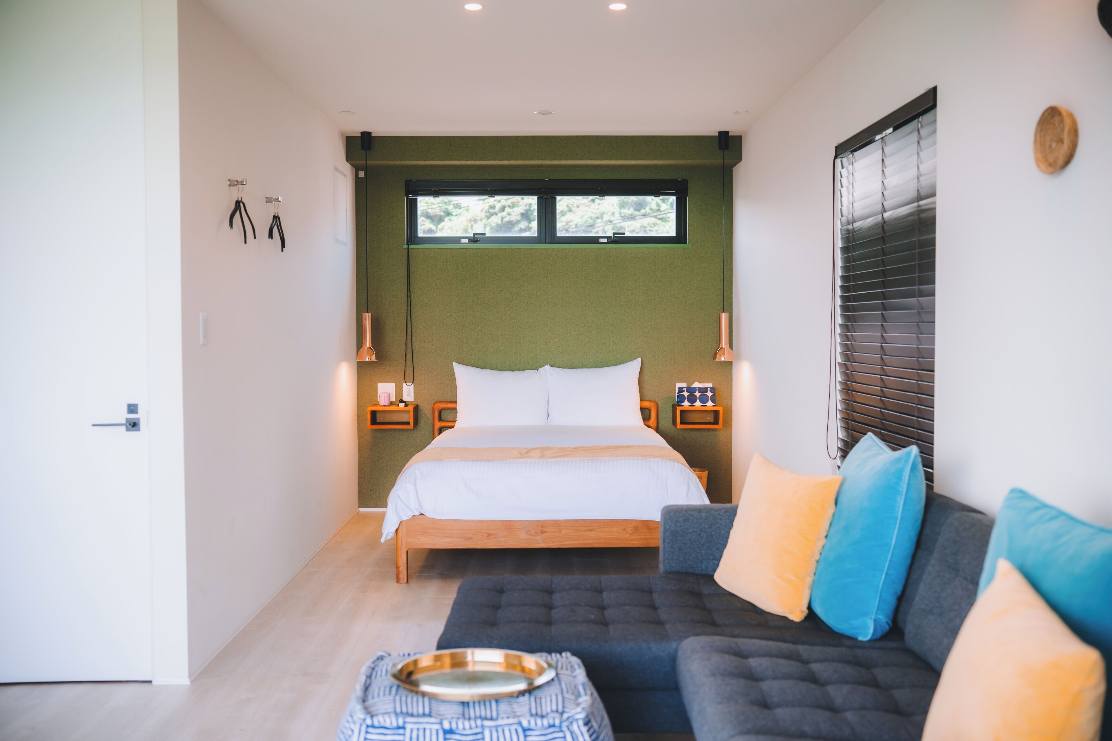 A bedroom with a bed, bedside tables, a sofa, and a window.