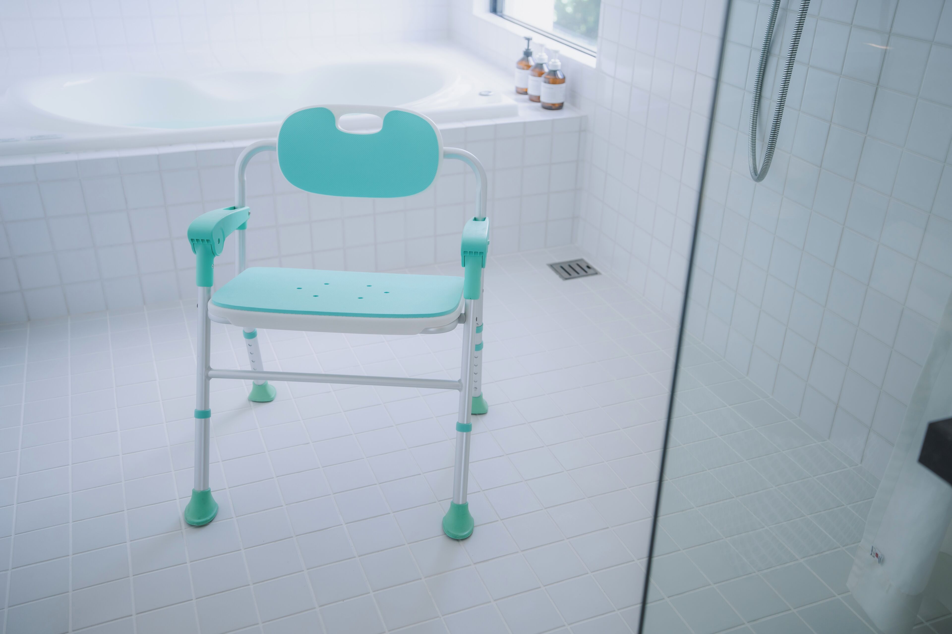 Een badkamer met een witte betegelde vloer, een wit ligbad en een babybadje in groen en wit.