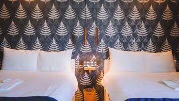 A hotel room with a bed, two pillows, a bedside table with a lamp, and a wall with a fern pattern.