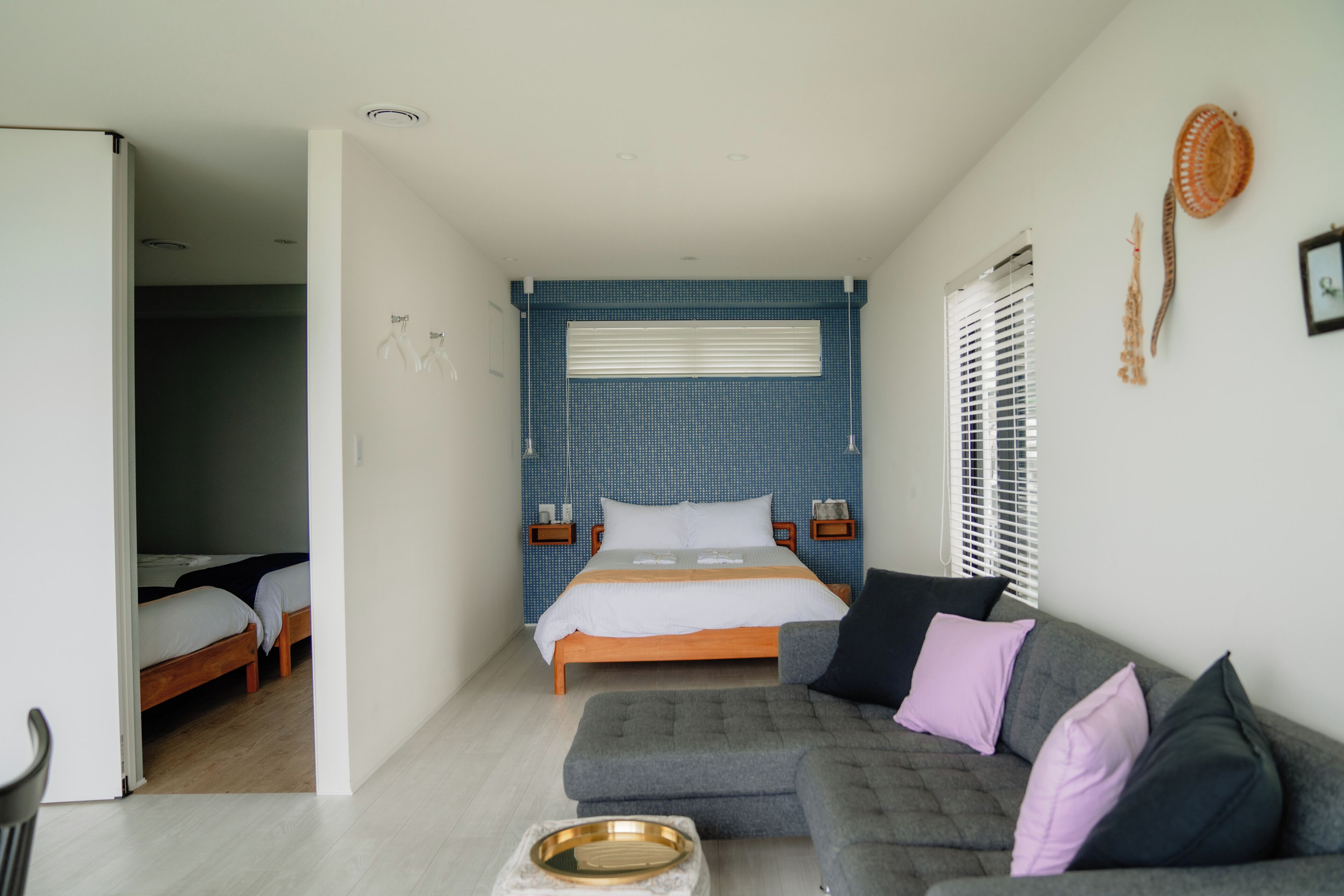 Ein Schlafzimmer mit einem Bett, einem grauen Sofa und einem kleinen Tisch mit Tablett.