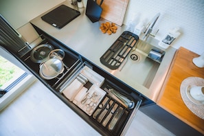 A kitchen with a built-in stove, a coffee machine, and a variety of utensils and cookware.