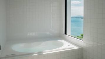Une salle de bain avec une baignoire et une vue sur la mer par une fenêtre.