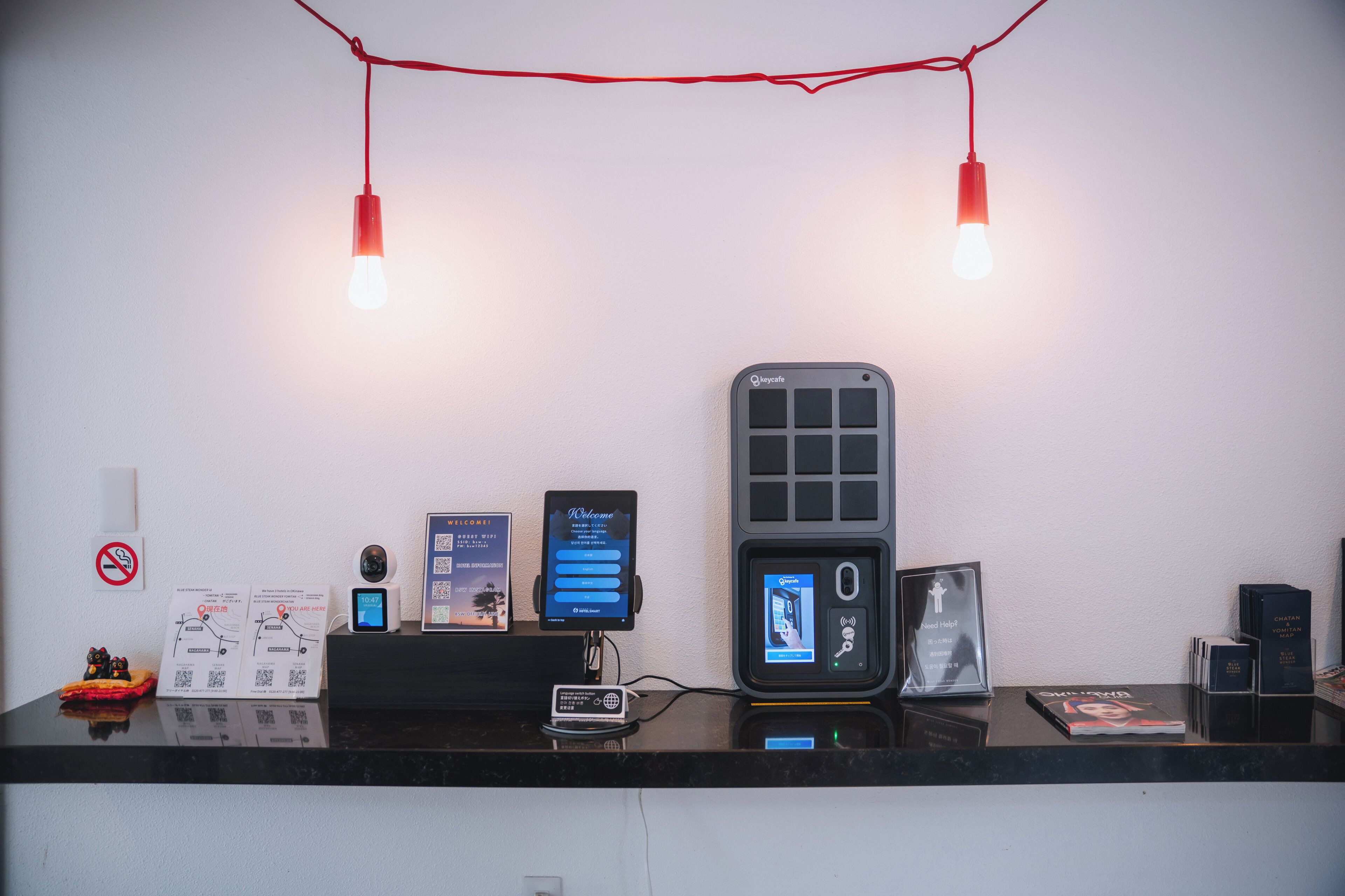 A reception desk with a digital kiosk, a security camera, and a no-smoking sign.