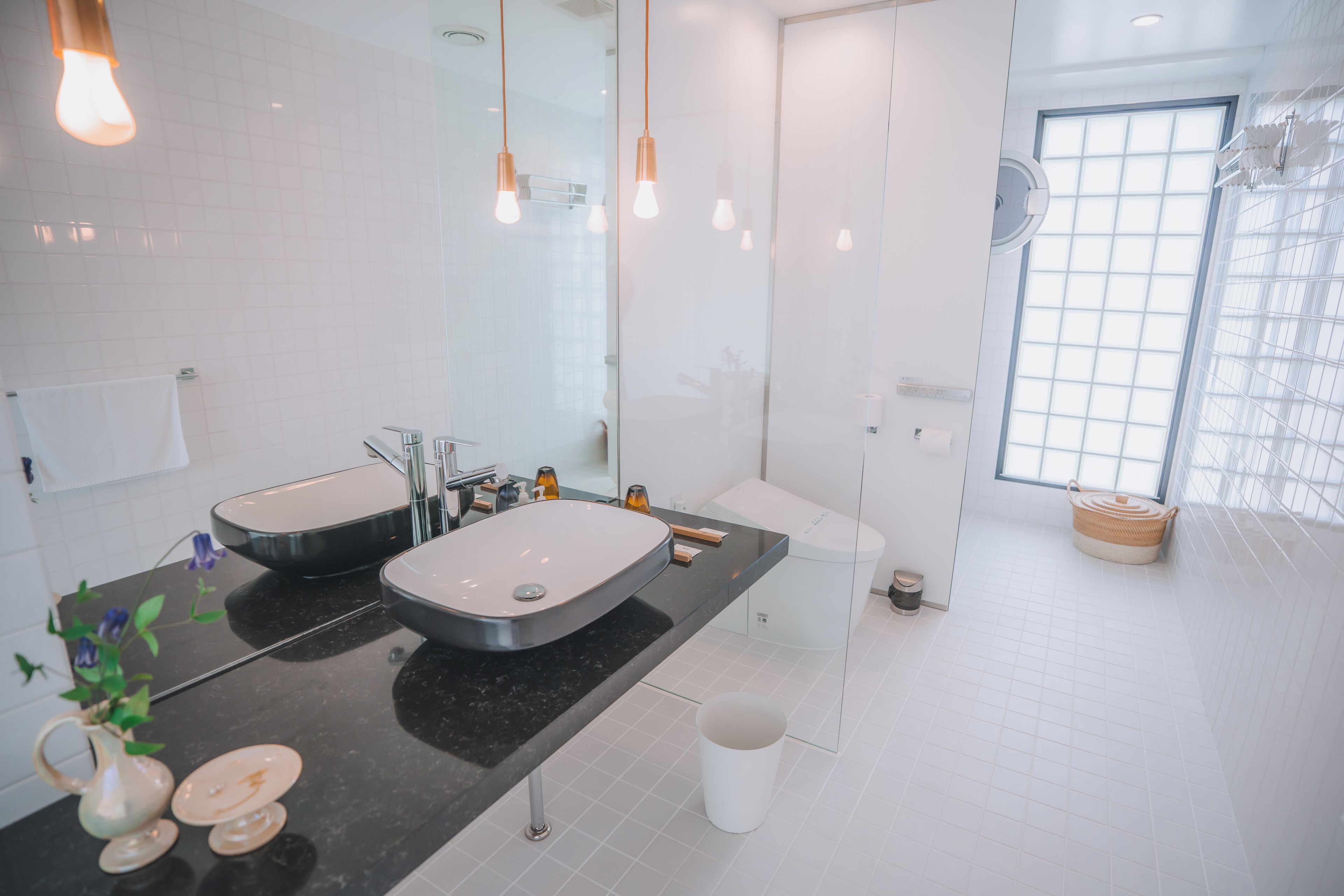 A modern bathroom with two sinks, a large mirror, and a window providing natural light.