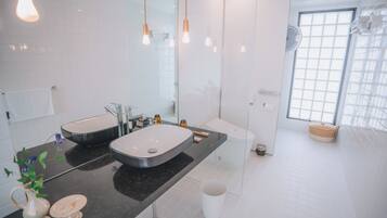A modern bathroom with two sinks, a large mirror, and a window providing natural light.