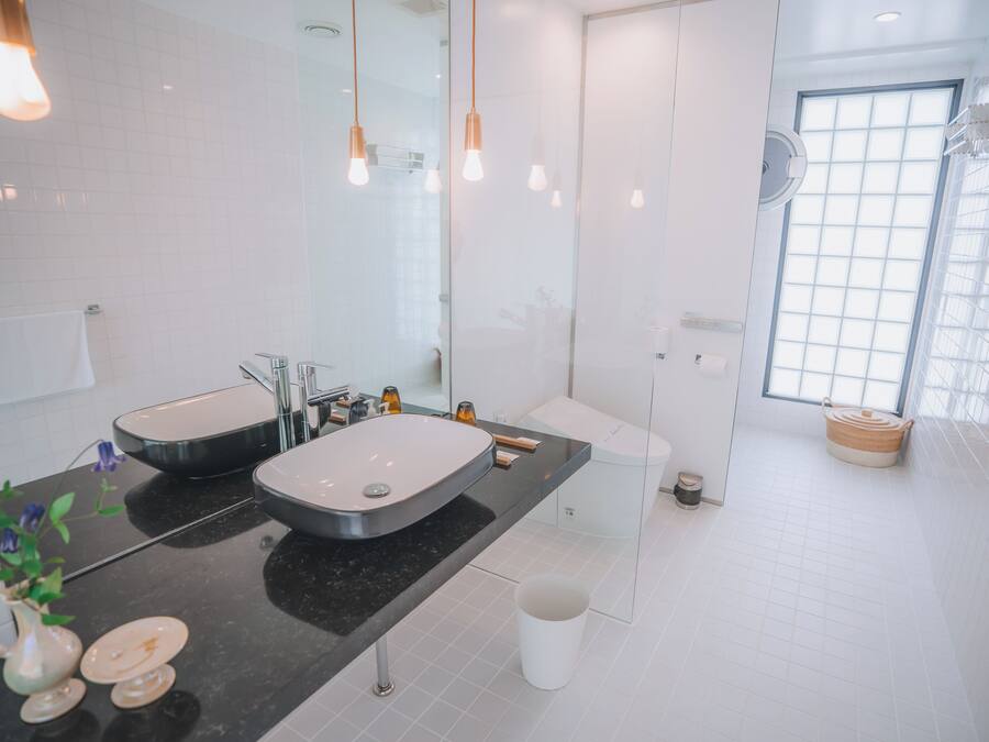 A modern bathroom with two sinks, a large mirror, and a window providing natural light.