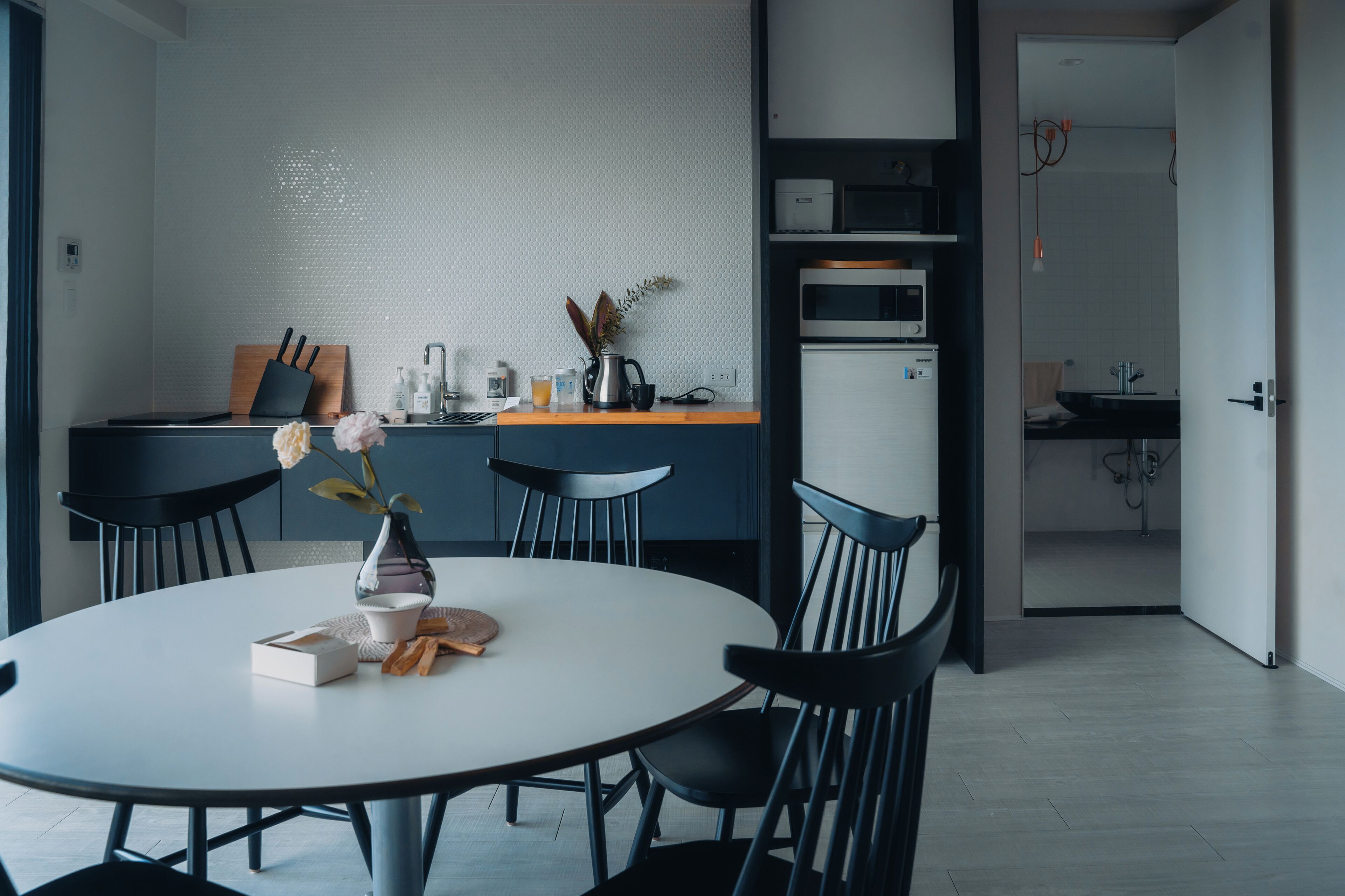 A modern kitchen with a white countertop, black chairs, and a round dining table.