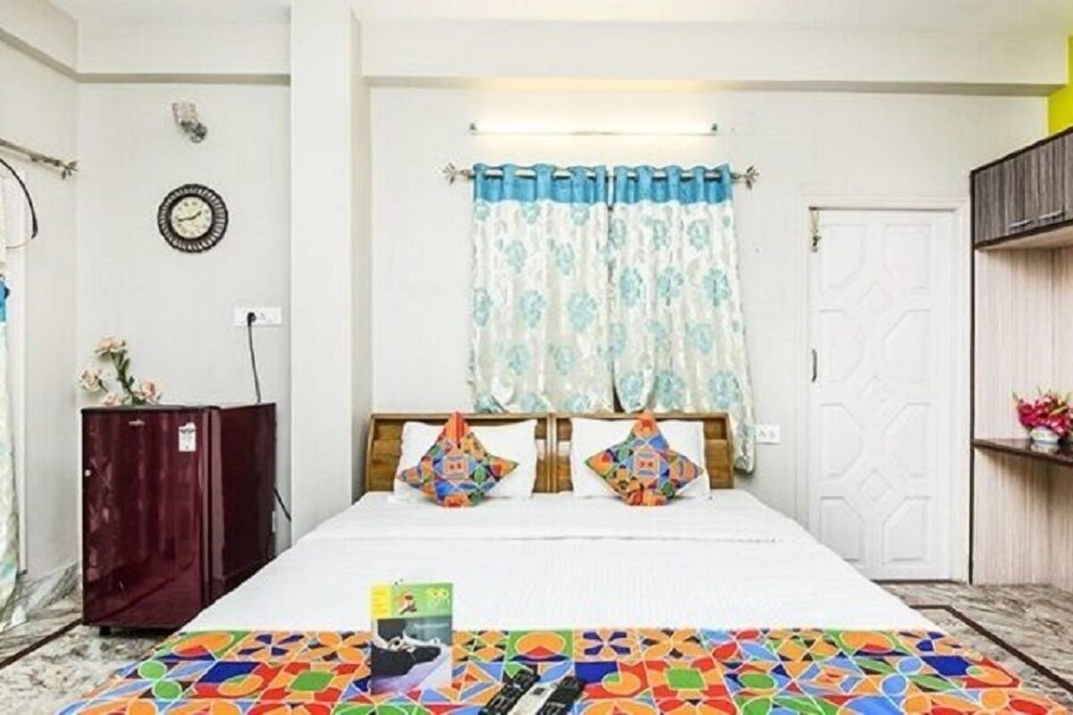 A bedroom with a bed, a wardrobe, a clock, and a window with curtains.