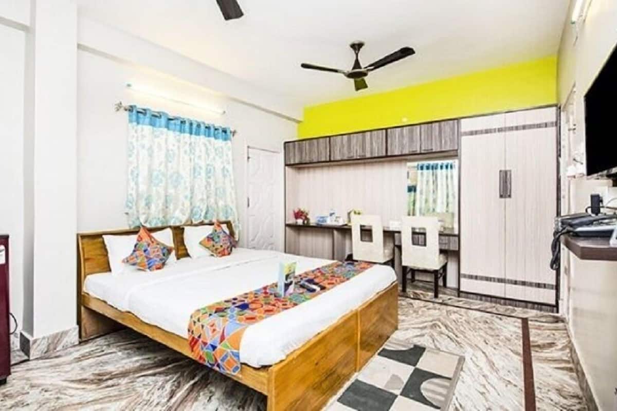 A bedroom with a bed, a desk, a wardrobe, and a ceiling fan.