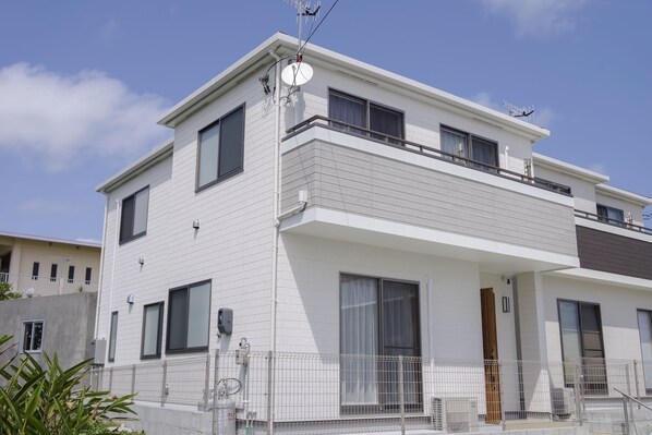 A modern two-story building with a flat roof, large windows, and a balcony.