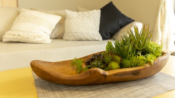 A wooden bowl with green plants on a table. - Hyakuna Terrace (Nanjo)