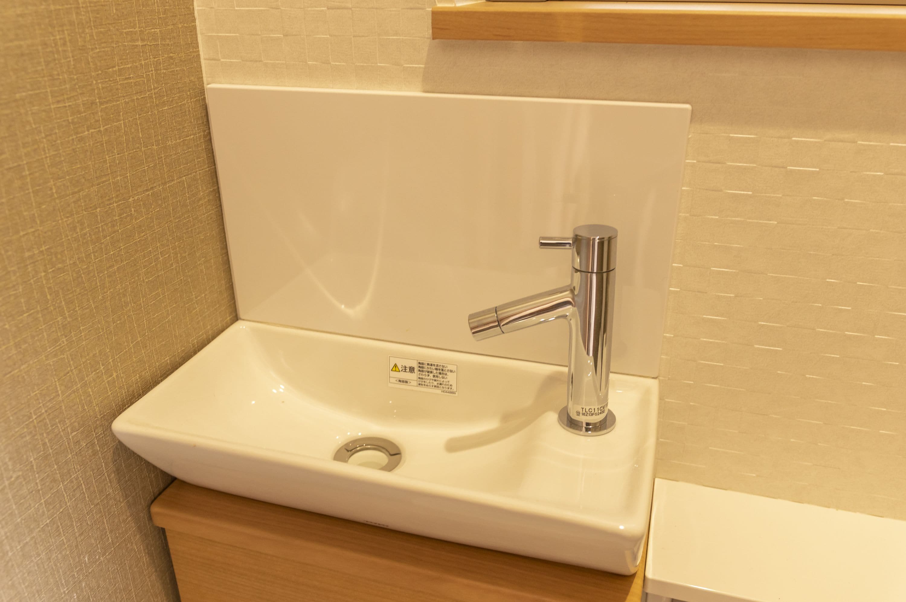 A white bathroom sink with a chrome faucet, a wooden countertop, and a tiled backsplash.