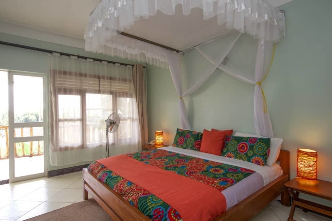 Un dormitorio con cama, cortinas, un ventilador y dos lámparas de noche.